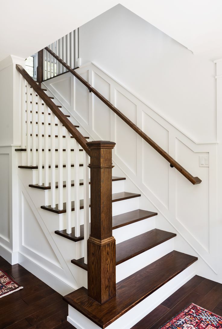 a white staircase with wooden handrails and wood flooring in a home's entryway