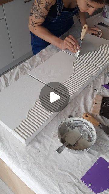 a woman is working on some kind of art project in her home studio with purple and white paint