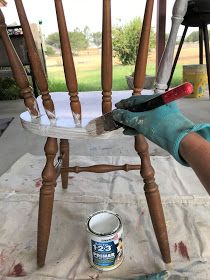 a person painting a wooden chair with white paint and a pair of gloves on it