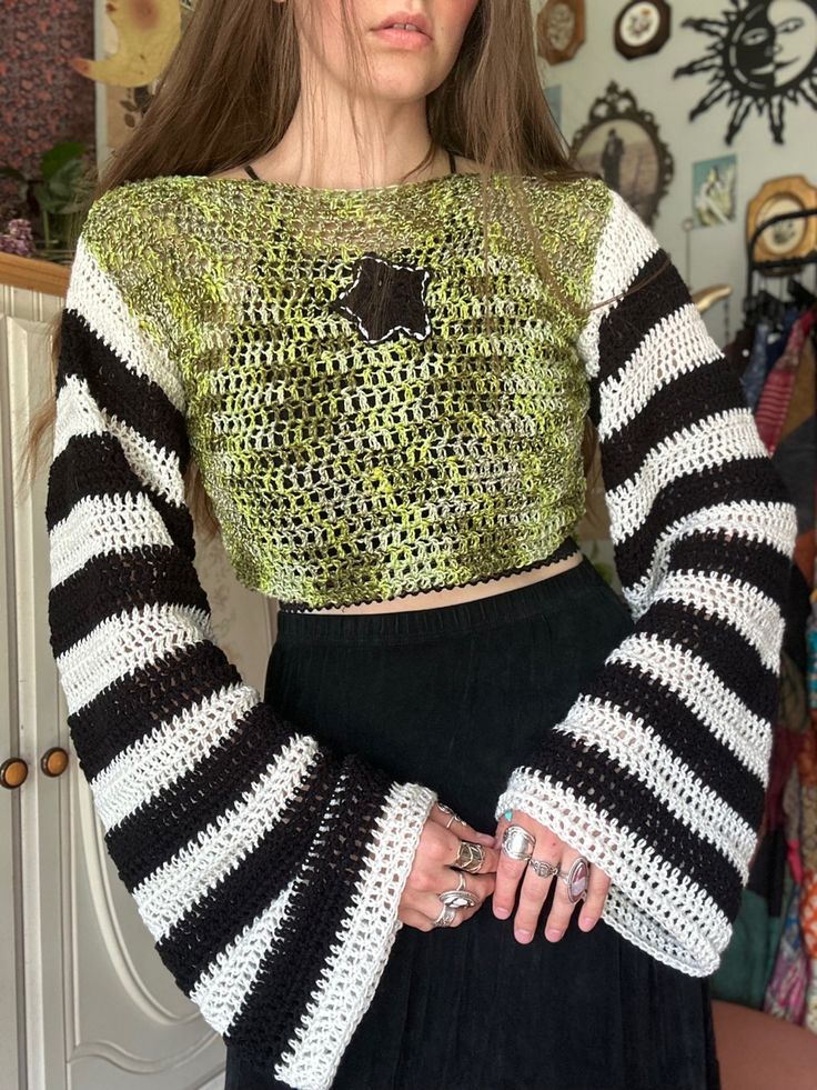 a woman wearing a black and white striped crop top with long sleeves standing in front of a closet