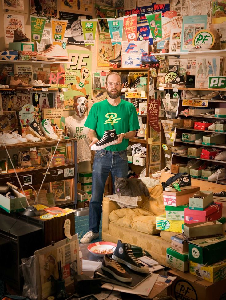 a man standing in front of a store filled with shoes and other items on display