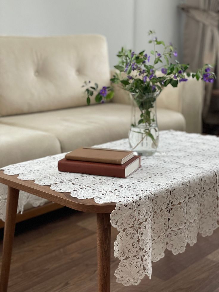 a table with a book and flowers in a vase on top of it next to a couch