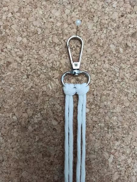 a pair of blue leather key chains hanging from a hook on a cork board wall