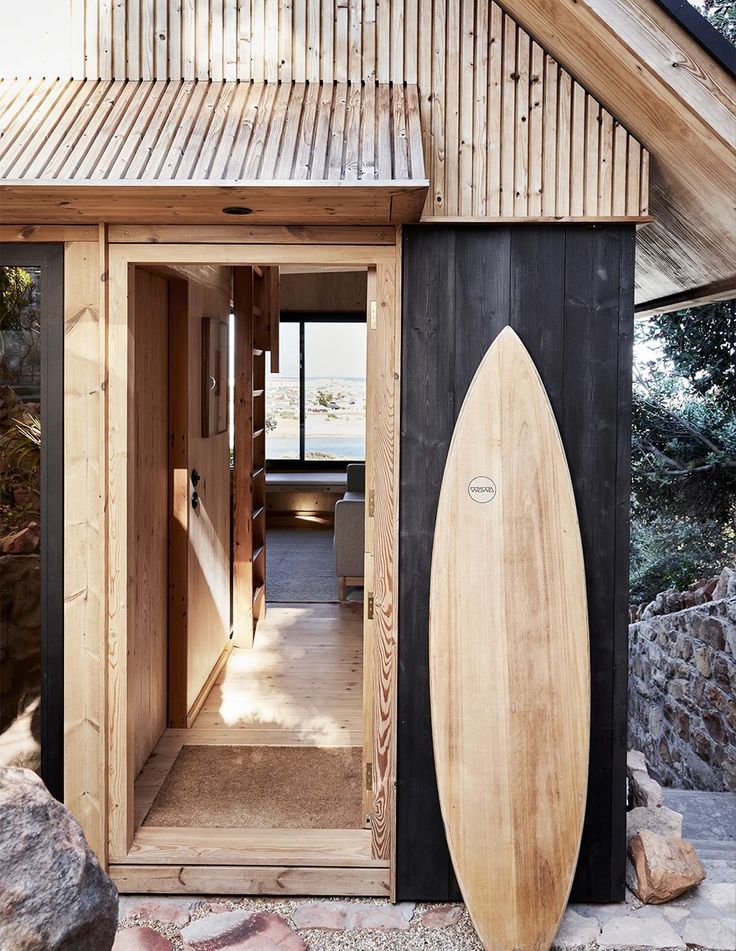 there is a surfboard in the doorway of this small building that looks like it's made out of wood