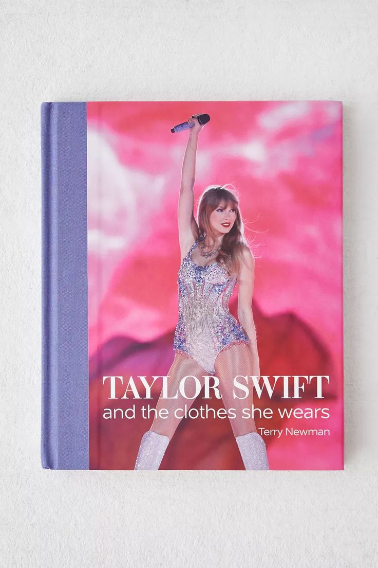 the book taylor swift and the clothes she wears is displayed on a white surface with a pink background