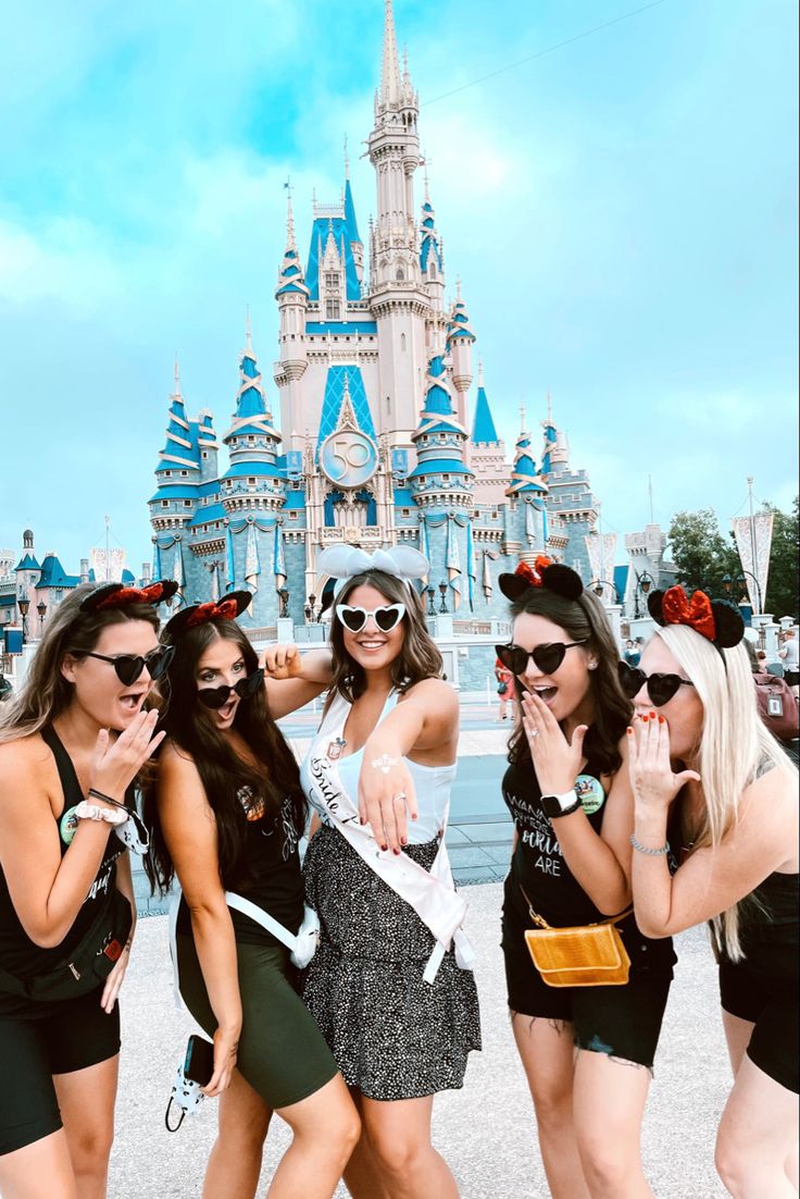 four girls posing in front of a castle with their hands on their hipss and wearing sunglasses