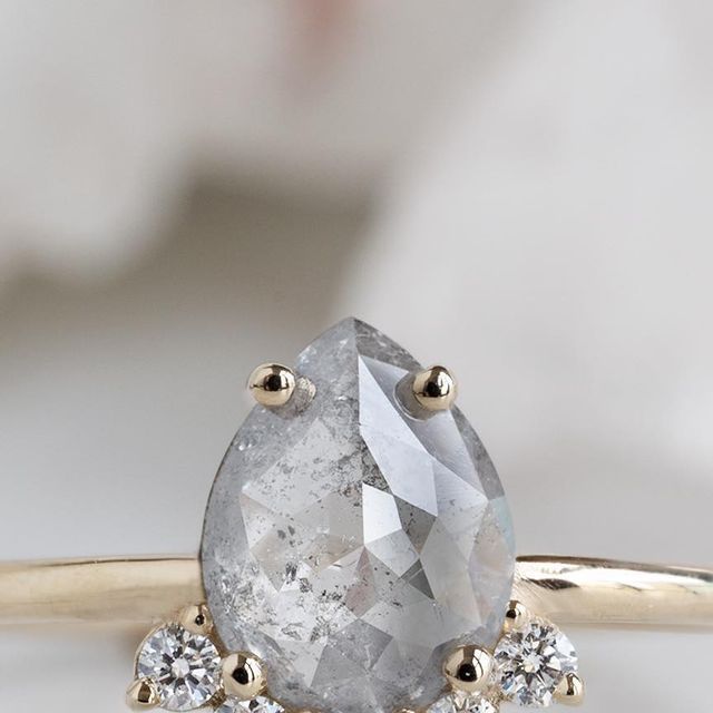 an engagement ring with a pear shaped diamond surrounded by three smaller round brilliant cut diamonds