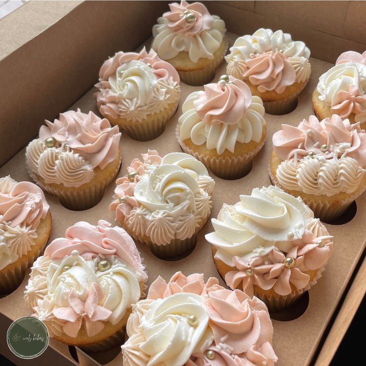 a box filled with lots of cupcakes covered in frosting and pink icing