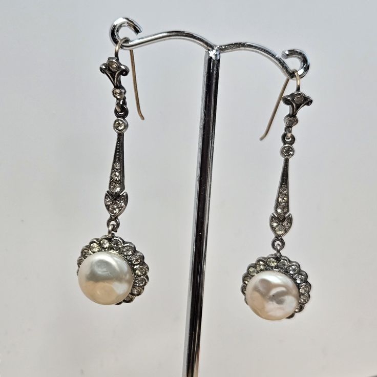 Embrace vintage elegance with these stunning sterling silver drop earrings. Inspired by Victorian designs, they feature shimmering paste pearls and simulated diamonds for a truly captivating look. Key Features: Metal: Sterling Silver (Marked "sil") Gemstones: Paste Pearls & Simulated Diamonds Style: Victorian-inspired drop earrings Size: 48mm x 14.5mm (approximately) Why Choose These Earrings? Vintage Charm: Capture the elegance of a bygone era with these beautiful Victorian-style earrings. Spar Vintage White Diamond Earrings For Formal Occasions, Classic Silver Drop Diamond Earrings, Victorian Pearl Earrings For Anniversary, Ornate Drop Diamond Earrings For Formal Events, Ornate Drop Diamond Earrings For Formal Occasions, Antique Drop Pearl Earrings For Formal Occasions, Ornate Diamond Drop Earrings For Formal Occasions, Antique Pearl Drop Earrings For Formal Occasions, Antique Silver Pearl Earrings For Anniversary