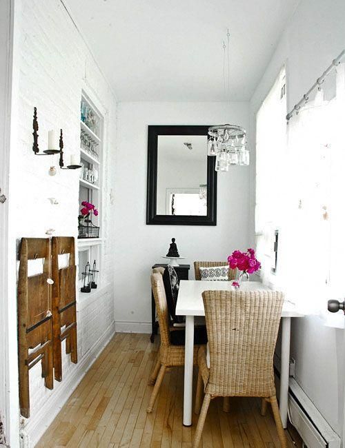 a dining room table with chairs and a mirror on the wall in front of it