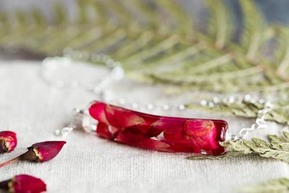 a necklace with red flowers and leaves on it