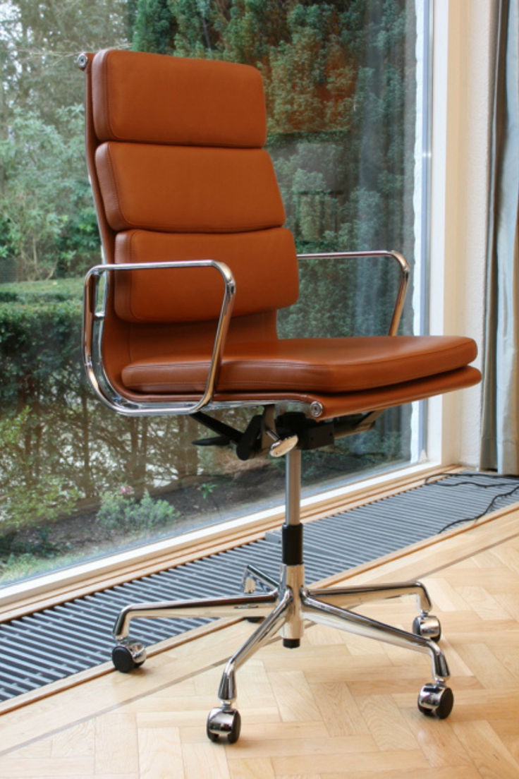 an office chair sitting on top of a hard wood floor in front of a window