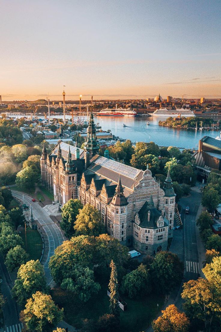 an aerial view of a large building next to a river and trees in the foreground