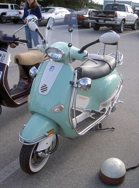 a scooter is parked in a parking lot next to a person on a motorcycle