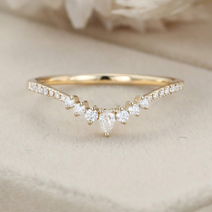 a gold ring with three diamonds on it and a white flower in the back ground