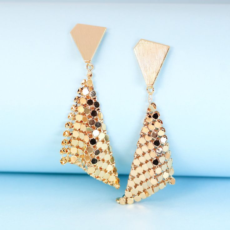 These geometric gold plated earrings will add instant sparkle and shine to any outfit. The handkerchief-inspired dangle design creates movement when you walk, catching the light in a unique way. The triangle stud backs ensure they'll stay put all night long, through dancing, laughing and all the festivities. Perfect party earrings for fashion-forward gals seeking a statement accessory that stands out from the crowd. Materials: 24k gold plated brassDimensions: 2.61 x 0.92 in Jewelry Care: See more information about how to care for your jewelry here. Shipping Policy: Orders will be shipped within 1-3 business days. Economy shipping will take 7-14 days to arrive and standard shipping is 1- 4 days for U.S. orders. International shipping time is depended on the country and per shipping method. Triangle Gold Metal Earrings, Gold Triangle Metal Earrings, Trendy Gold Triangle Earrings, Trendy Geometric Earrings For Party, Gold Plated Dangle Chandelier Earrings For Party, Gold Geometric Earrings For Party, Geometric Gold Earrings For Party, Gold Plated Chandelier Dangle Earrings For Parties, Gold Plated Chandelier Earrings For Party