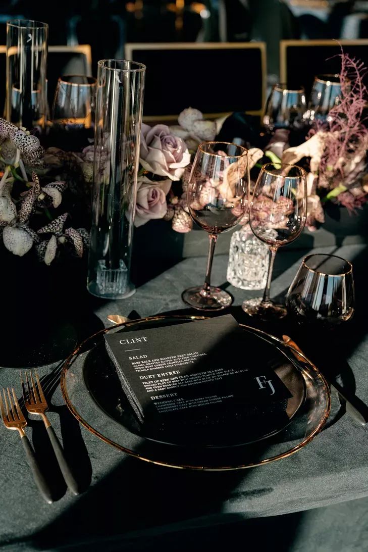 the table is set with wine glasses, plates and utensils for an elegant dinner