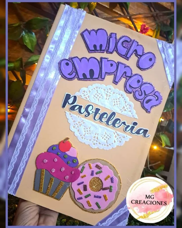 a hand holding up a sign that says micro empresso pasteleria with cupcakes on it