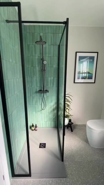 a bathroom with a green tiled shower and toilet