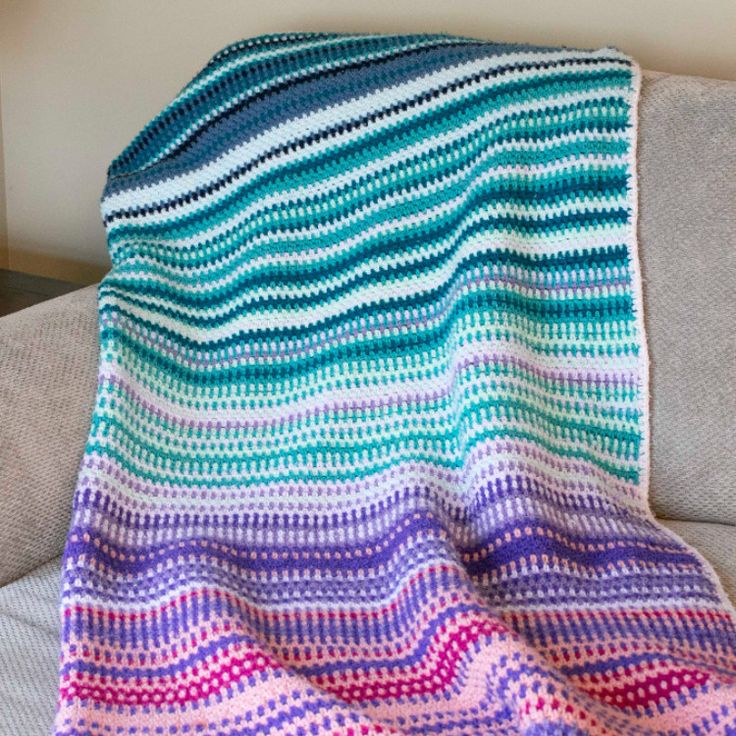 a crocheted blanket sitting on top of a couch