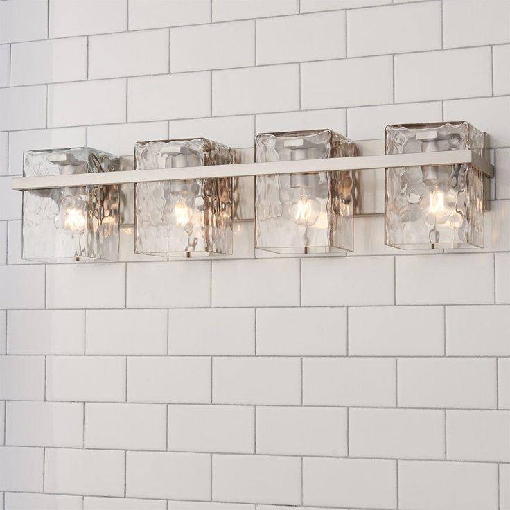 a bathroom light that is on the side of a white brick wall with four lights