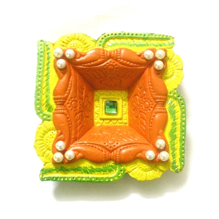 an orange, yellow and green brooch with pearls in the center on a white background