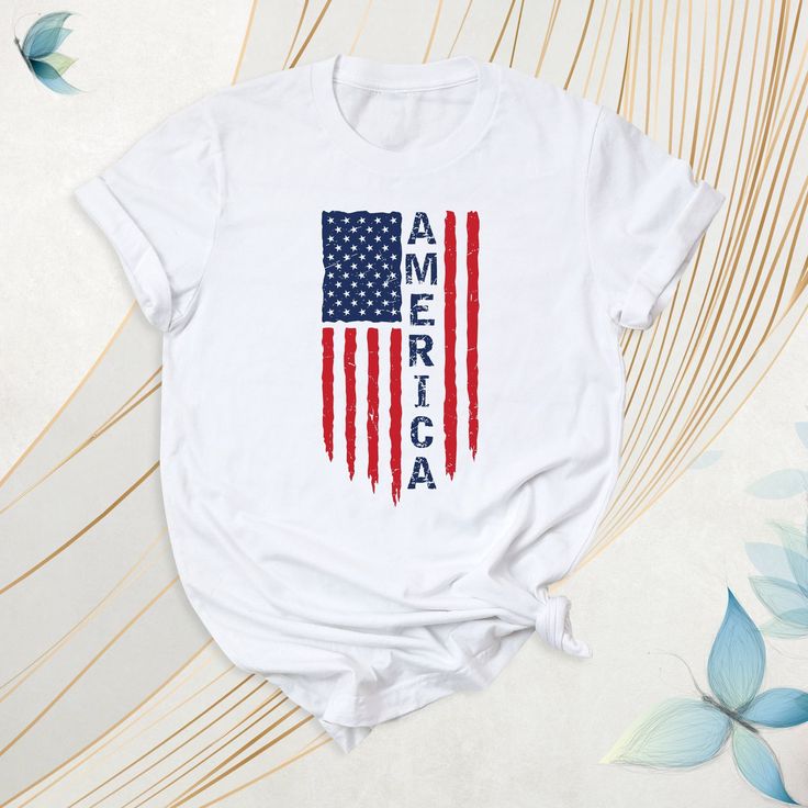 America Shirt, USA Flag Tshirt, Independence Day Tee, Red White And Blue Outfit, Patriotic American Flag Shirt, American Flag Tee, USA Shirt. These t-shirts often feature a design bearing the national symbols and colors of the United States. They are also frequently preferred during election periods. How To Order: - Please, check all tees color and  size charts. - Select your shirt size, color and quantity from the drop-down menu. - Click the "Add to cart" button. You can come back to add more i Casual Short Sleeve T-shirt With American Flag, American Red T-shirt With Graphic Print, Casual Red T-shirt With American Flag Print, Red Crew Neck T-shirt With Flag Print, Patriotic Red Cotton T-shirt, White T-shirt With American Flag, Red Casual T-shirt With Flag Print, Red Cotton Top With American Flag Print, Casual Red T-shirt With Flag Print