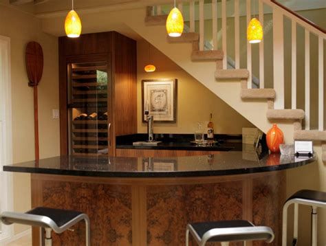 a kitchen with two stools and a bar in the middle, under some stairs