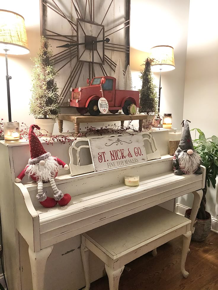 an old white piano is decorated with christmas decorations and gnome figurines on top