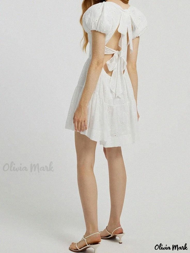 Olivia Mark - Sweet White Princess Dress with Square Neckline, Open Back, Floral Details, Bow Tie, and Sensual Atmosphere White Dress With Lace-up Back For Day Out, White Mini Dress With Lace-up Back For Spring, White Backless Daywear Dress, Short Sleeve Mini Dress With Lace-up Back For Summer, Summer Short Sleeve Mini Dress With Lace-up Back, Feminine White Mini Dress With Lace-up Back, White Short Sleeve Mini Dress With Tie Back, Summer Dresses With Lace-up Back And Short Sleeves, Short Sleeve Summer Dress With Lace-up Back