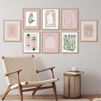 a living room with pink and green art on the wall next to a wicker chair