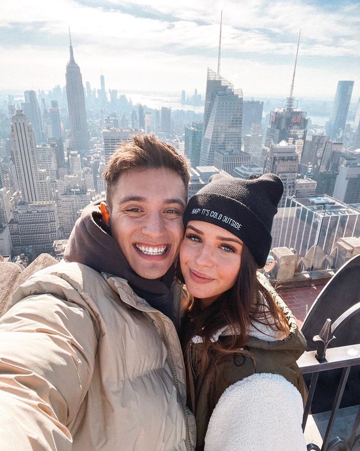 a man and woman taking a selfie on top of a building