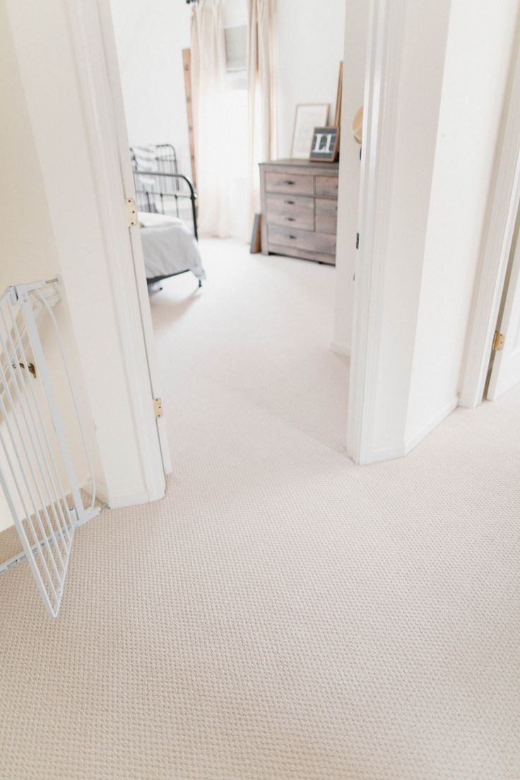 an empty bedroom with white walls and carpet