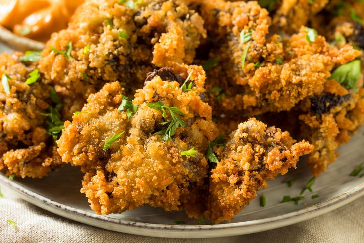 some fried food is on a plate with sauce and parmesan cheese breadcrumbs