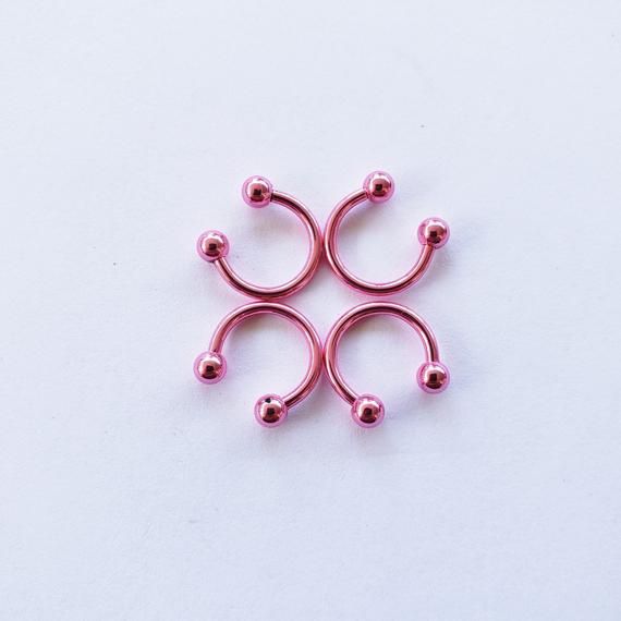 four pink balls are arranged in the shape of a snowflake on a white surface