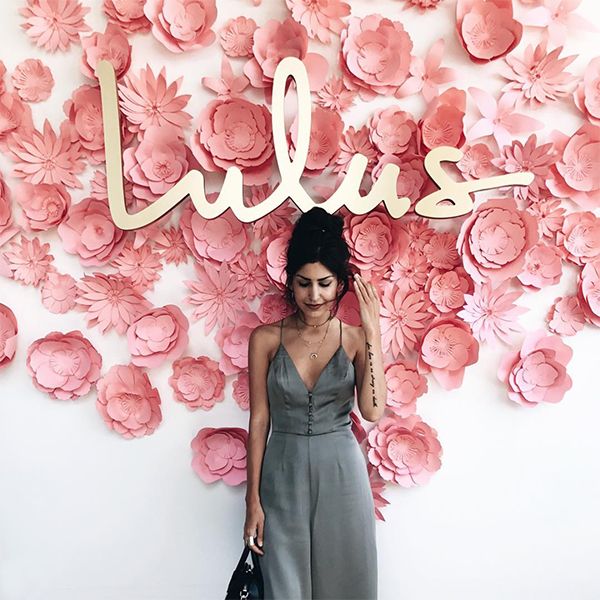 a woman standing in front of a flower wall with the word lulis on it