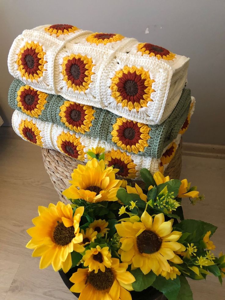 the sunflowers are next to some crocheted blankets on top of each other