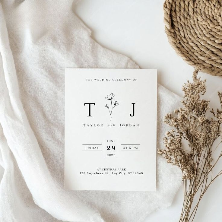 the wedding stationery is laid out next to some dried flowers and a straw hat