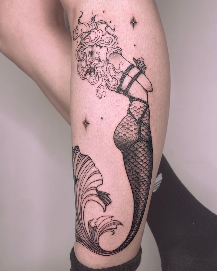 a woman's leg with a mermaid tattoo on it