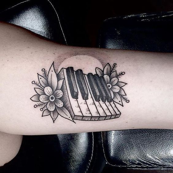 a black and white photo of a piano with flowers on it's side arm