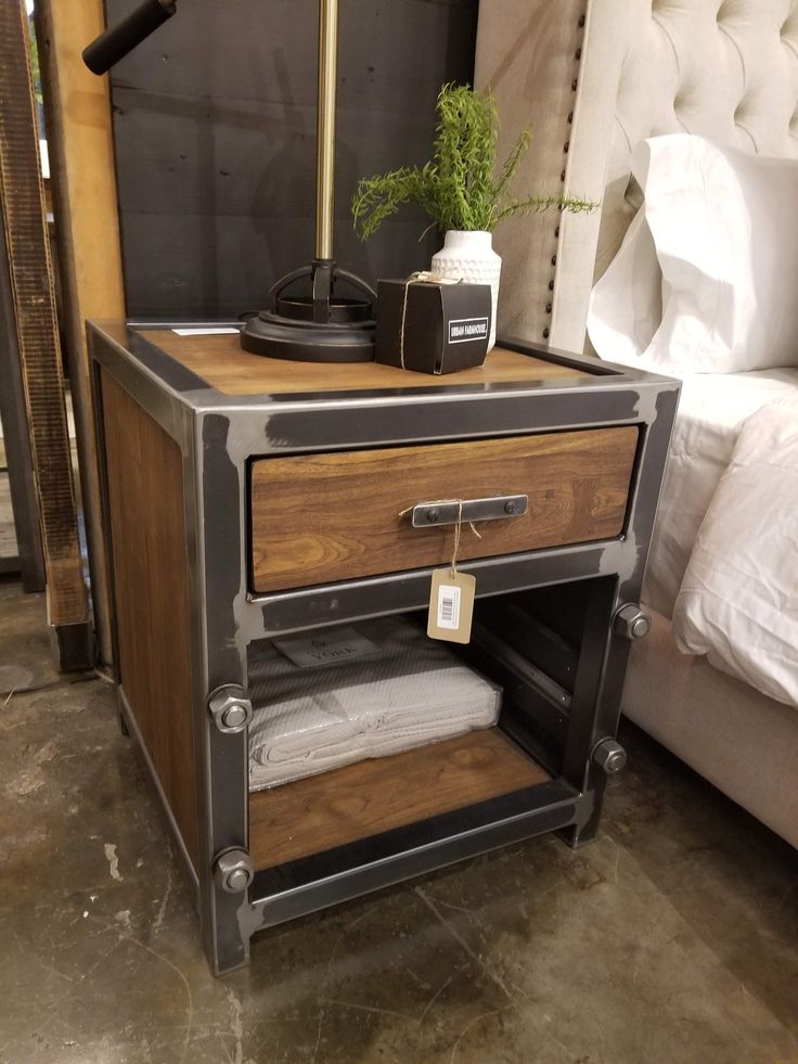 a bedside table with two drawers and a phone on it, next to a bed