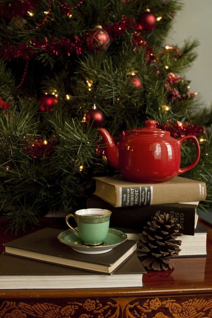 a red teapot sitting on top of two books next to a christmas tree