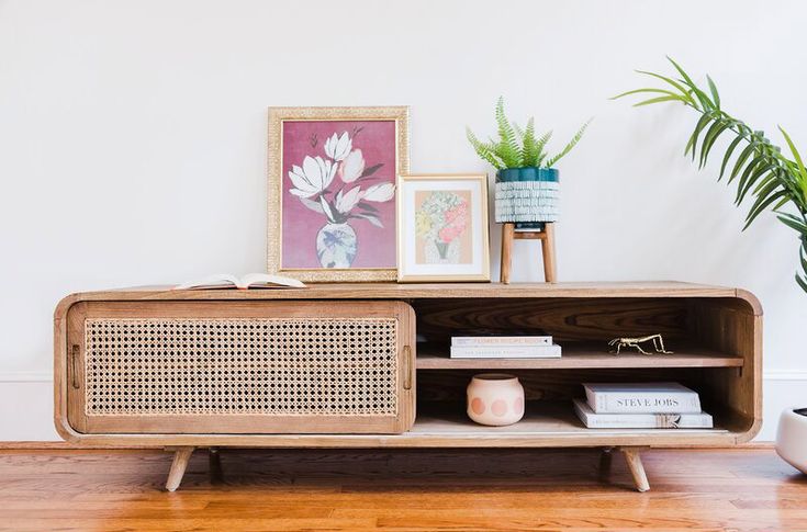 a wooden cabinet sitting on top of a hard wood floor next to a potted plant