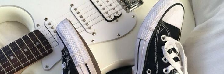 a pair of black and white shoes are next to an electric guitar