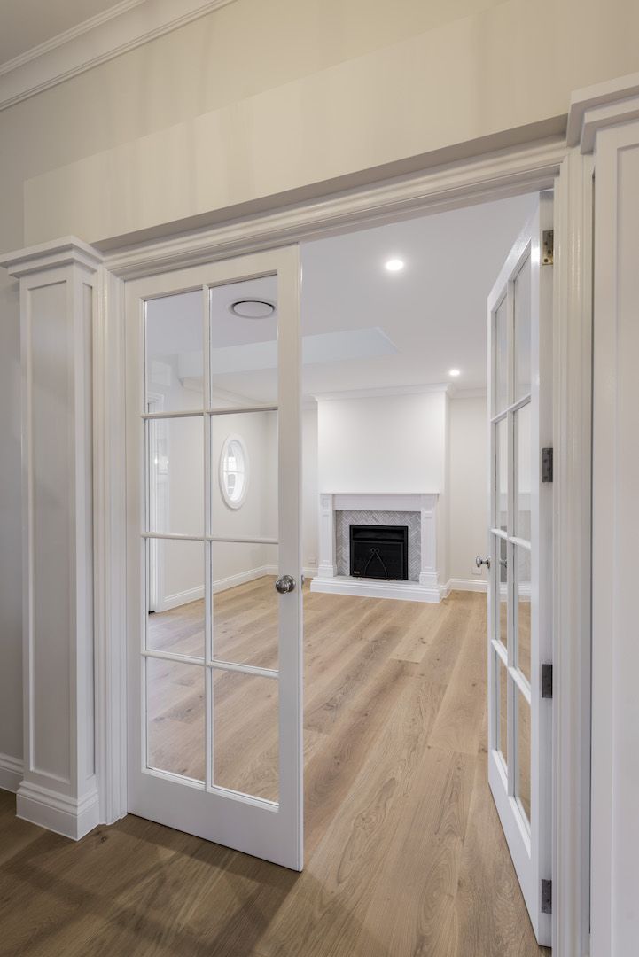 an empty living room with white walls and wood flooring is seen from the doorway