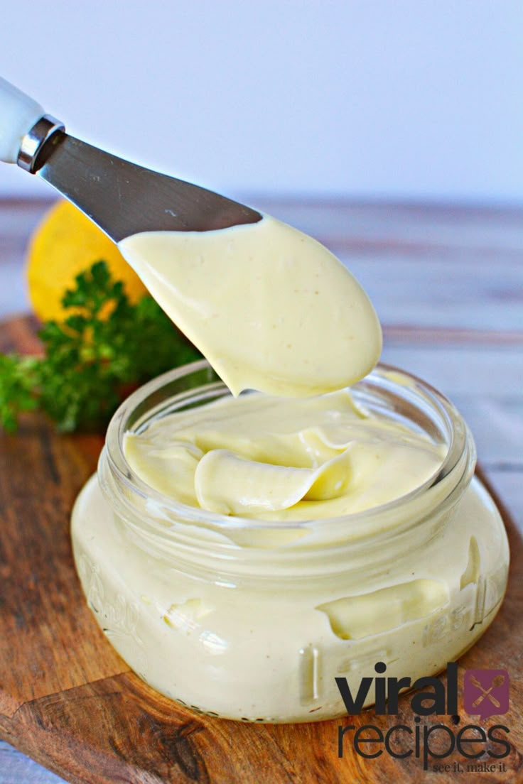 a spoon is lifting some mayonnaise out of a jar on a cutting board