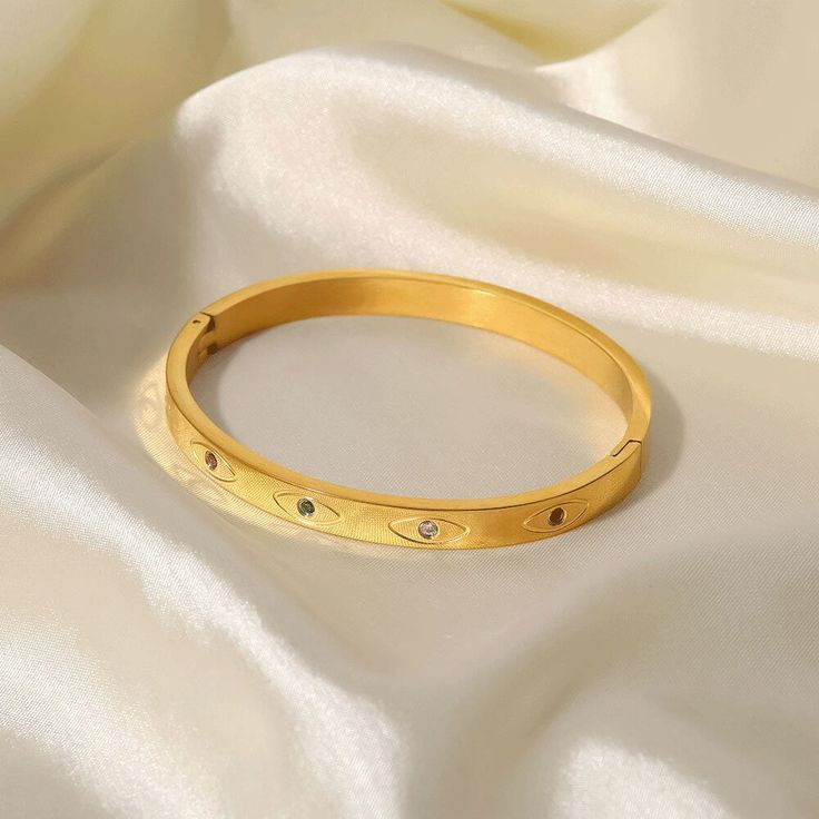 The Evil Eye Bracelet, with its iconic symbol set on an 18k gold-plated band, offers both style and mystical protection. This culturally rich piece adds a meaningful touch to your ensemble, blending tradition with modern elegance. Gold Promise Bracelet, Gold Symbolic Bracelets For Everyday, Everyday Symbolic Gold Bracelets, Gold Bangle Bracelets For Promise, Gold Tarnish Resistant Bracelets For Promise, Gold Tarnish-resistant Bracelets For Promise, Symbolic 14k Gold Bracelets, Spiritual Gold Bangle Bracelet, Symbolic Gold Bangle Bracelet