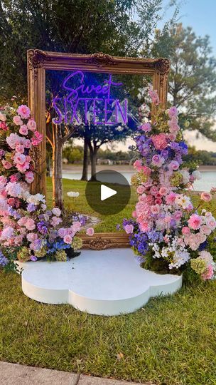 a mirror sitting on top of a grass covered field next to flowers and plants in front of it