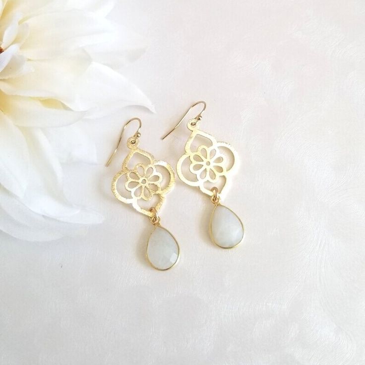 Make an elegant statement in these gorgeous Moonstone teardrop earrings.Earrings consist of a modern design brushed gold flower that is accented with a natural bezel set faceted Moonstone.Details:* Brushed Gold Flower Measures about 28 mm* Each flower is 14 k gold plated on brass,. Lead, nickel and cadminum free with a non tarnishing coat* Natural teardrop bezel set faceted Moonstone measuring about 14 mm* 14 k Gold Filled Ear Wires (not plated)* Earrings measure about 2 inchesAll jewelry includ Bride Earrings Gold, October Jewelry, Evening Earrings, Bride Earrings, Facepaint, Moonstone Earrings, Gold Flower, Gold Flowers, Leaf Earrings