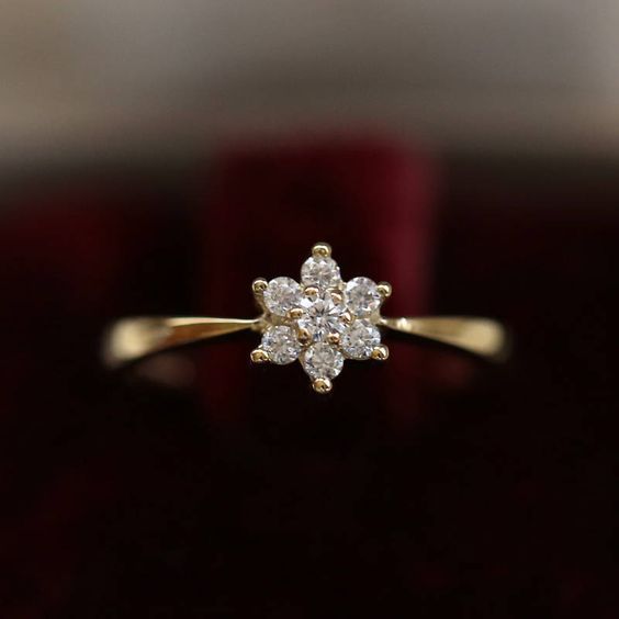 a yellow gold ring with white diamonds in it's center on a red velvet surface